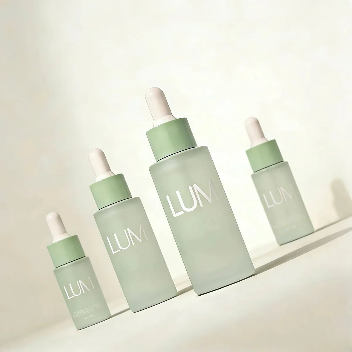 Clinical flat shoulder skincare packaging manufactured by Lumlun, featuring the LUM logo on a mint green glass dropper bottle.