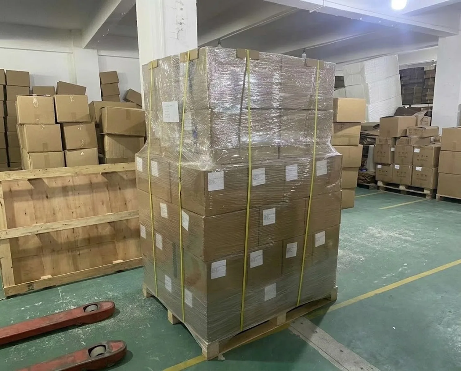 Tall stack of cardboard boxes securely wrapped in clear stretch film on a wooden pallet, ready for cosmetic packaging export
