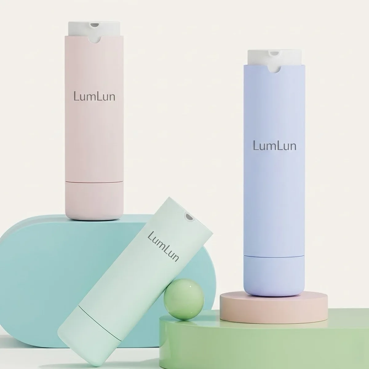 Three gradient spray refillable airless pump bottles in pastel pink, mint green, and lavender blue with arc-notch white pump heads — 30ml and 50ml ABS outer shell with replaceable PP inner refill, LumLun OEM serum and lotion packaging
