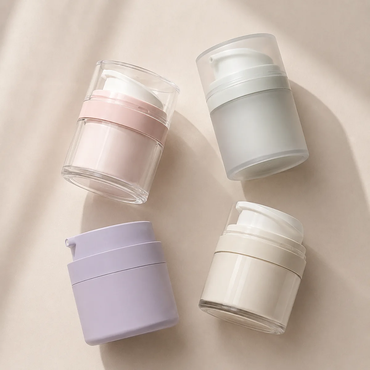 Four airless pump jars in pink, frosted white, purple matte and cream gloss finishes showing color and transparency options