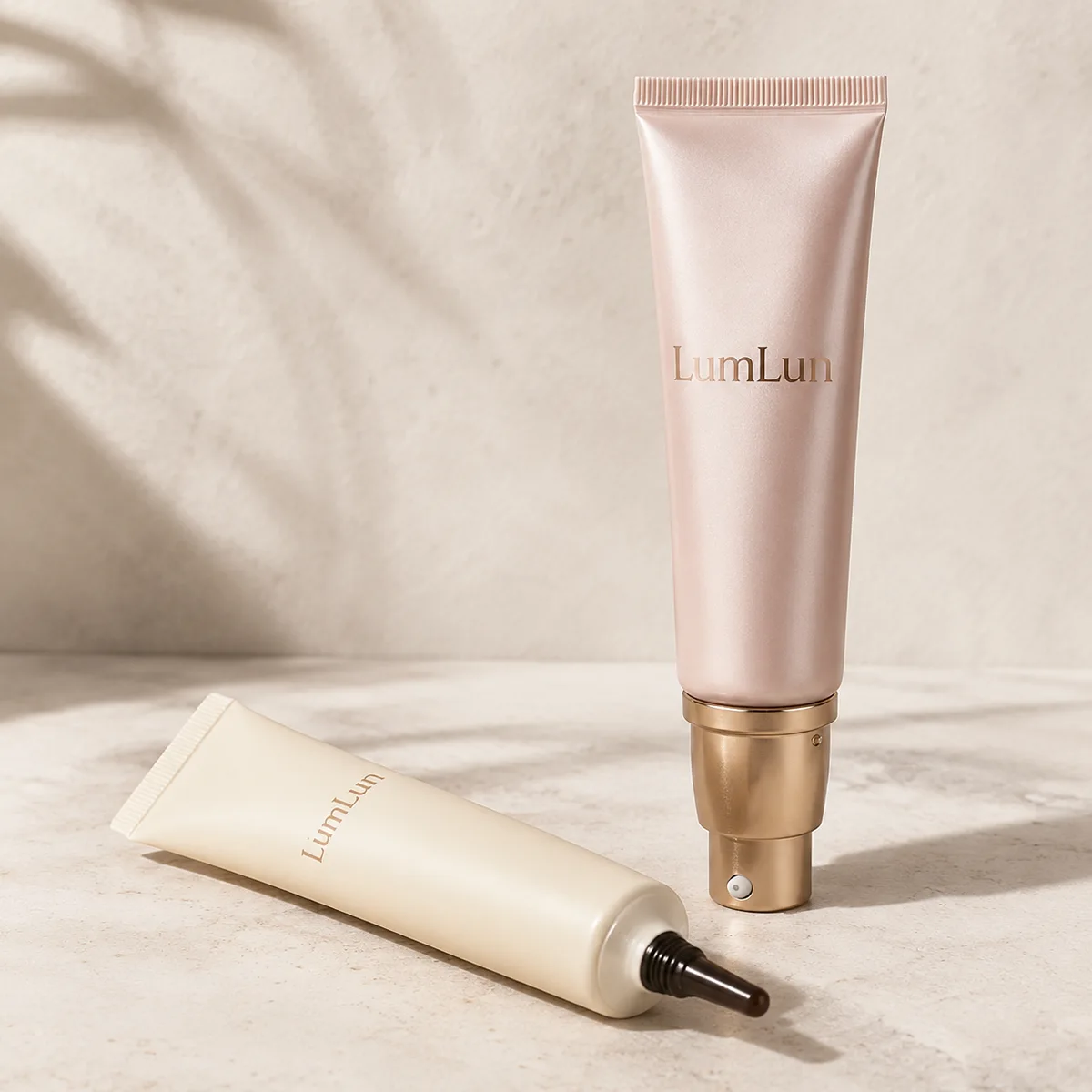 Two premium pearlescent LumLun cosmetic tubes with a gold metal applicator collar and a fine bronze metal nozzle tip for precise dosing