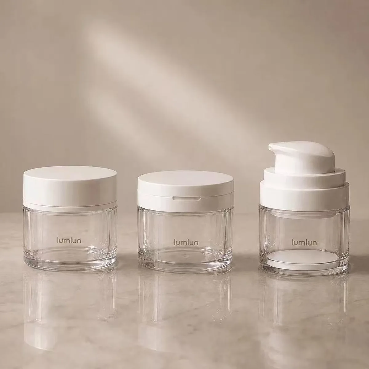 Three clear PETG LumLun cream jars showing screw cap, snap-on cap, and pump head closure options on warm beige background