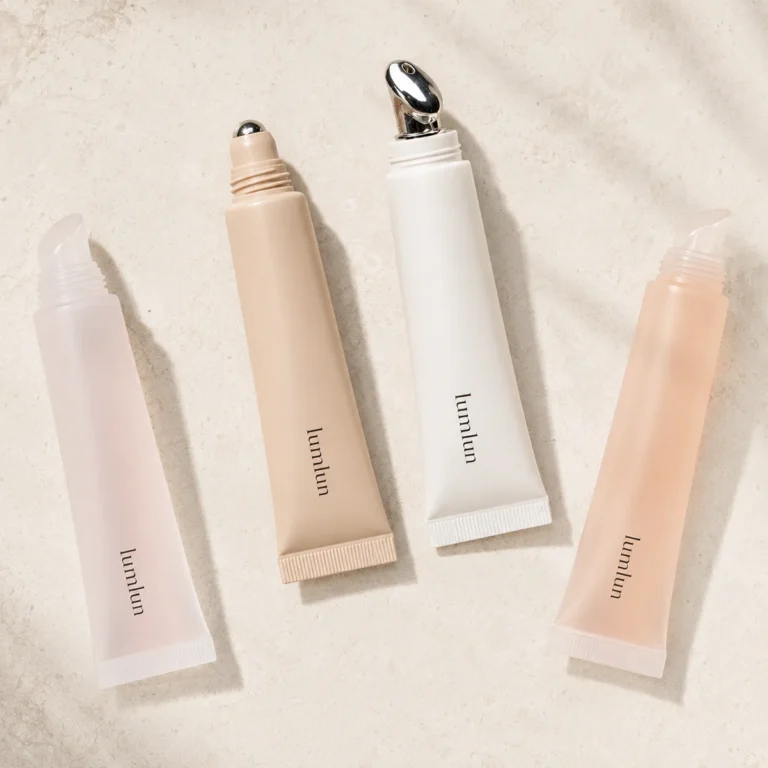 Flat lay of LumLun lip serum squeeze tubes with silicone, rollerball, and alloy massage applicator tips on a stone surface