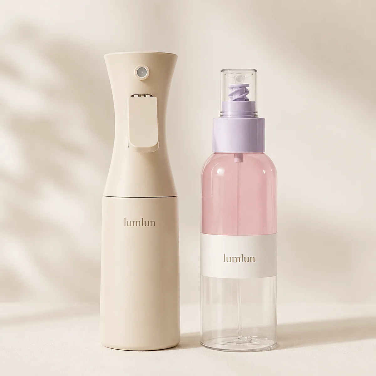 Beige continuous spray bottle beside a pink fine mist pump spray bottle showing two different spray mechanisms for skincare