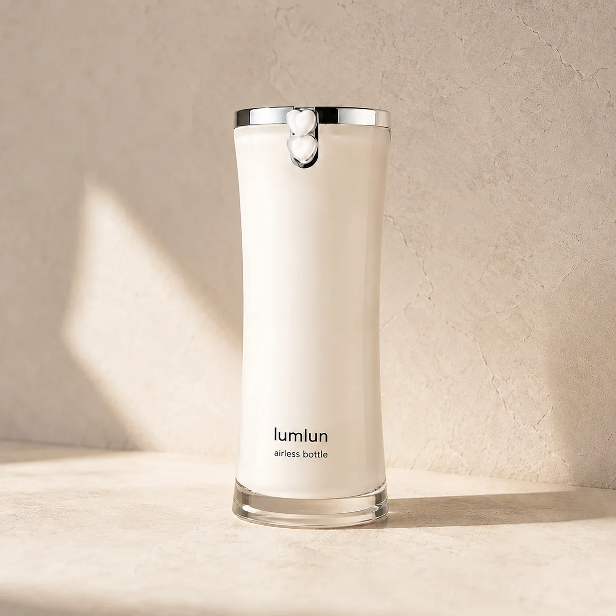 Lumlun airless serum bottle in cream color with a chrome rim and heart shaped pump detail.