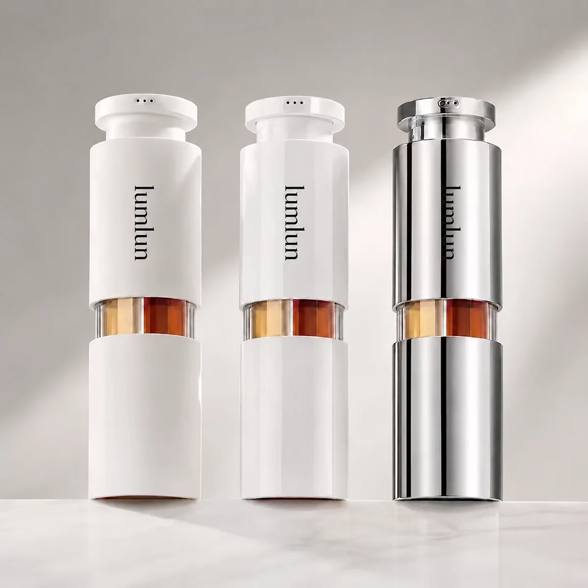 Three Lumlun multi-chamber airless bottles in white and silver finishes showing three-chamber structure and custom shell options for skincare brands