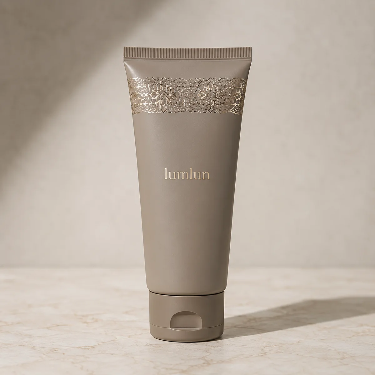 Premium taupe LumLun cosmetic tube with gold foil lace detail showing custom branding on a sustainable squeeze tube