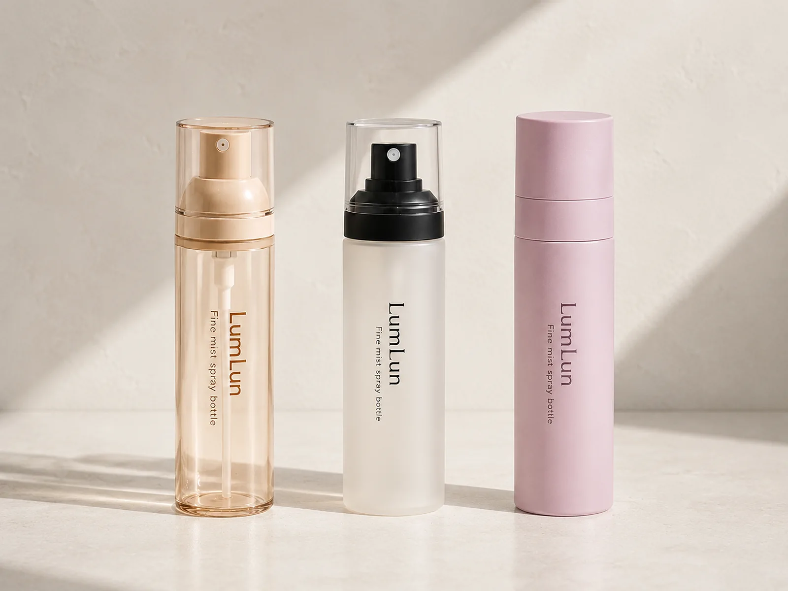 Three LumLun fine mist spray bottles in transparent amber, frosted white and matte pink finishes