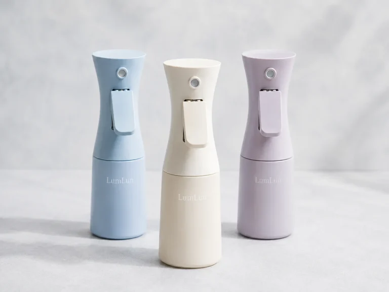 Three LumLun continuous mist spray bottles in pastel blue, ivory and lavender with ergonomic trigger designs
