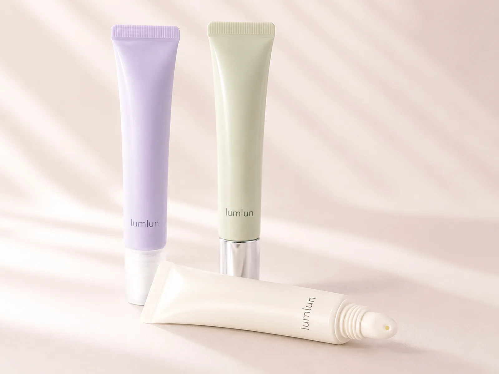 Three slim LumLun lip gloss squeeze tubes in clear, blush and pearl finishes with coordinated caps