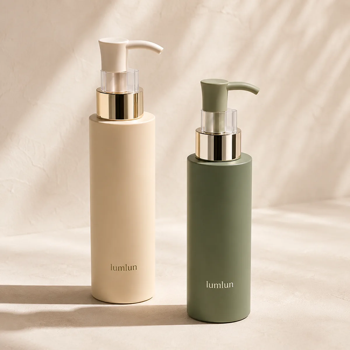 Cream and sage Lumlun lotion pump bottles shown side by side with gold collars on a warm background.