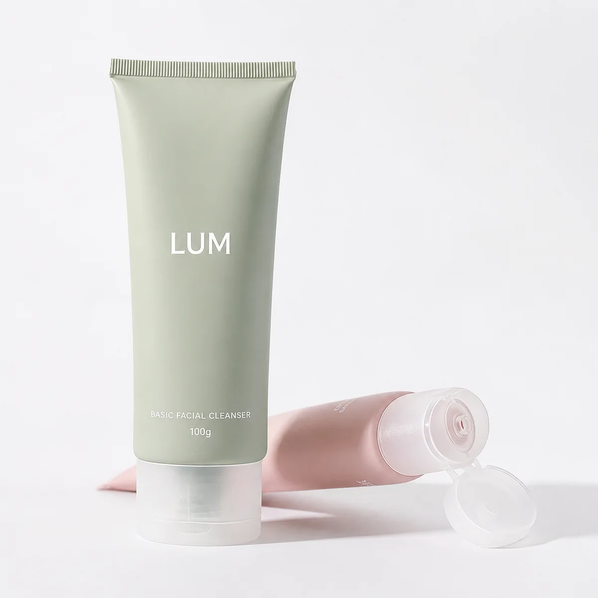 Two LumLun 100ml cosmetic soft tubes in pastel colors displayed in a minimal clean studio setup.