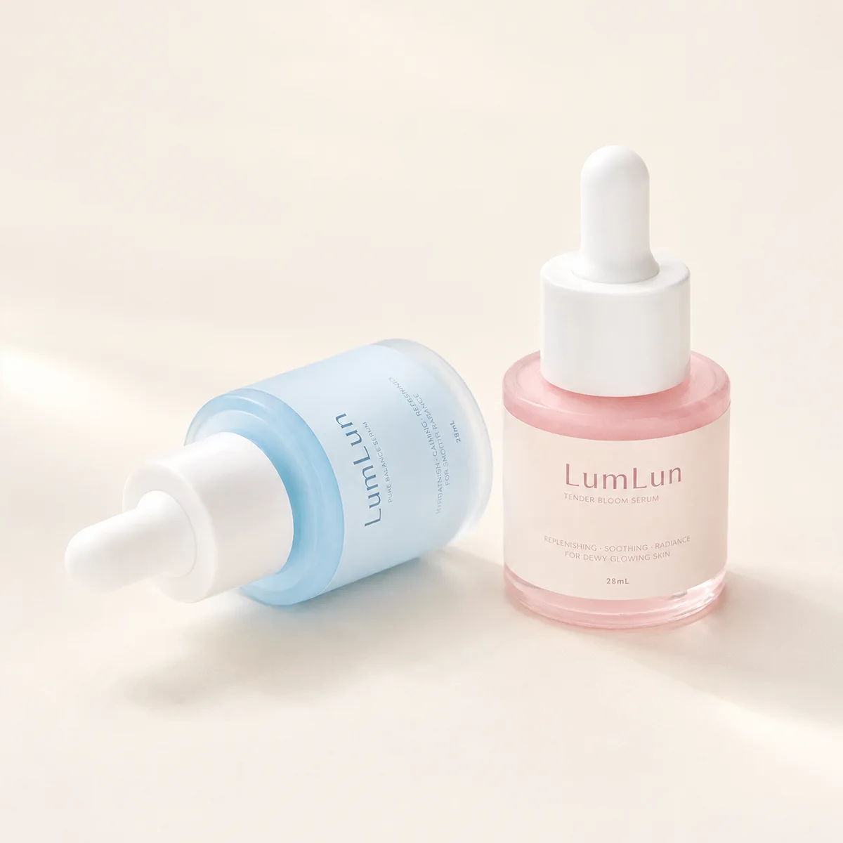 Lumlun 15ml flat shoulder glass dropper bottles in pink and blue, one standing and one lying down.