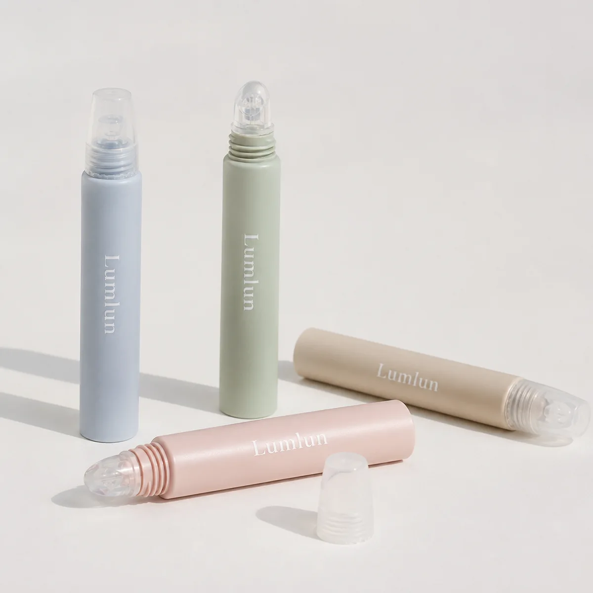 Four pastel 15ml PE lip balm squeeze tubes with clear silicone applicator tips, shown open and closed