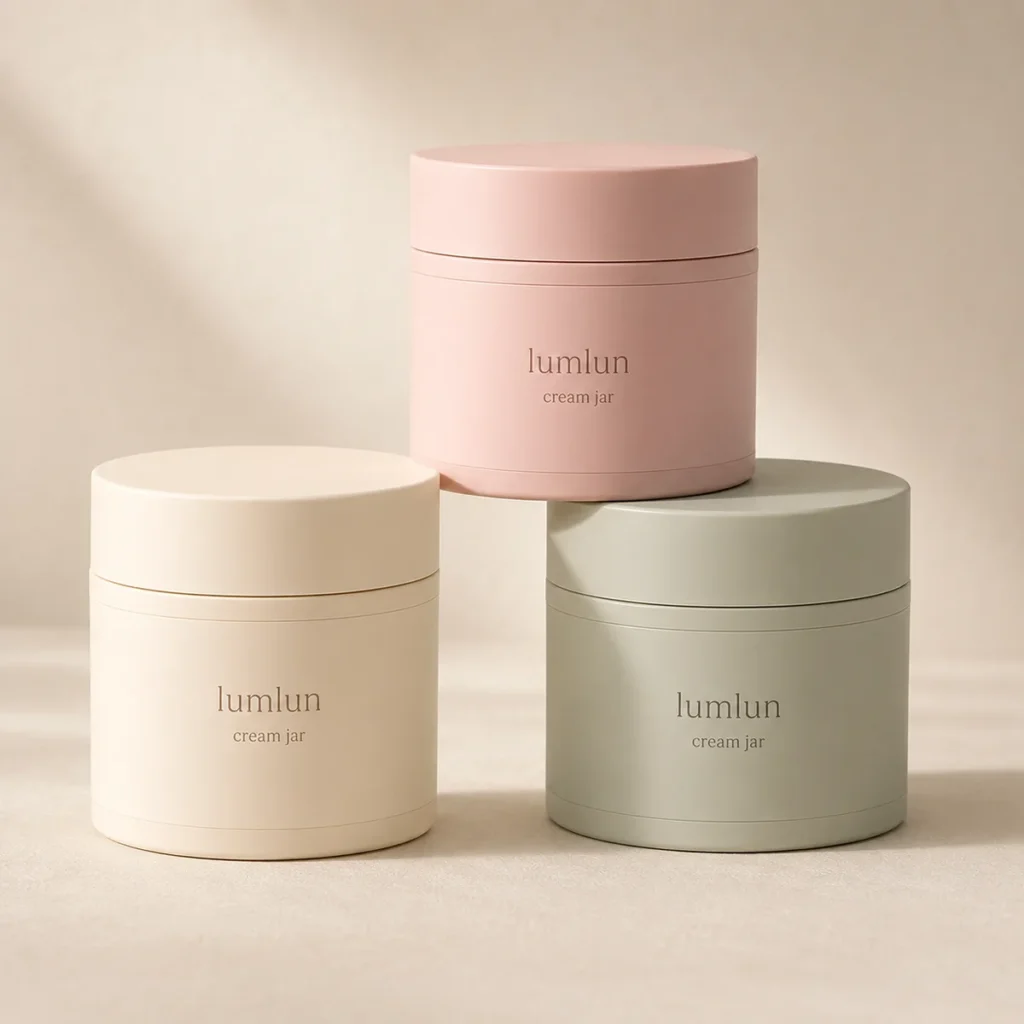 Three Lumlun cream jars in pink, cream, and sage tones on a minimalist beige set.