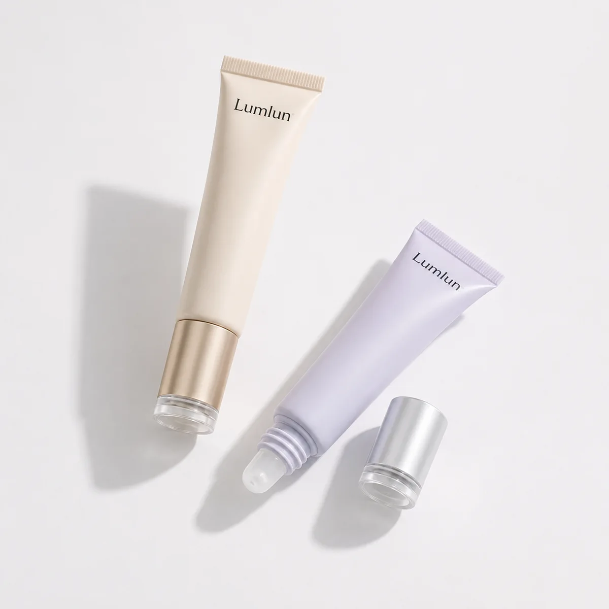 Two LumLun 19mm PE lip balm squeeze tubes displayed in a minimal studio setup with soft pastel tones.