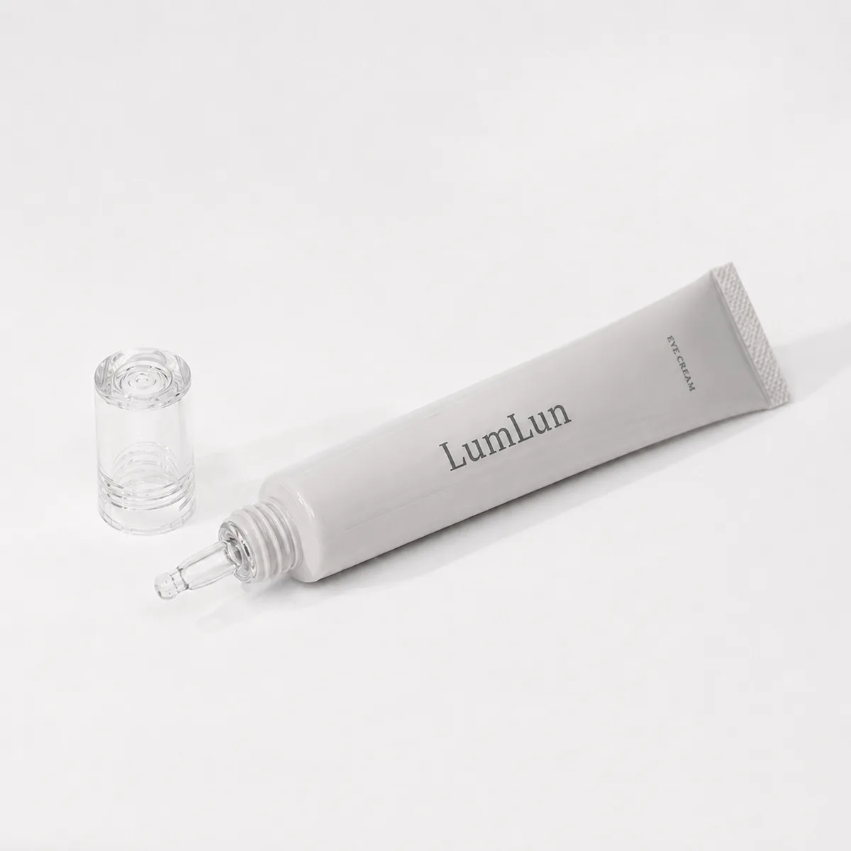 A single gray Lumlun eye cream squeeze tube with an exposed precision nozzle and clear cap beside it.