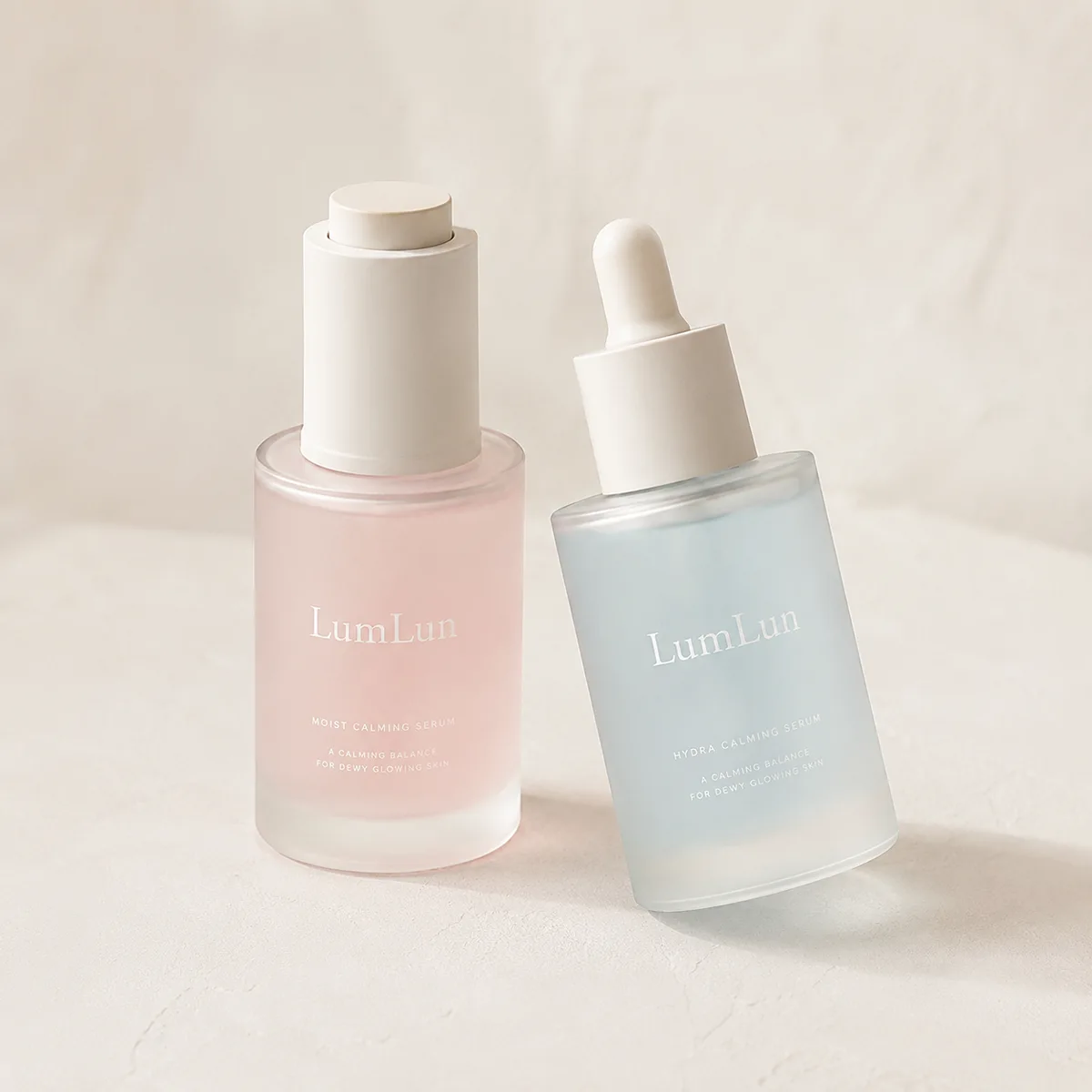 Lumlun 30ml glass dropper bottles in pink and blue, showing a white push-button cap and bulb dropper.
