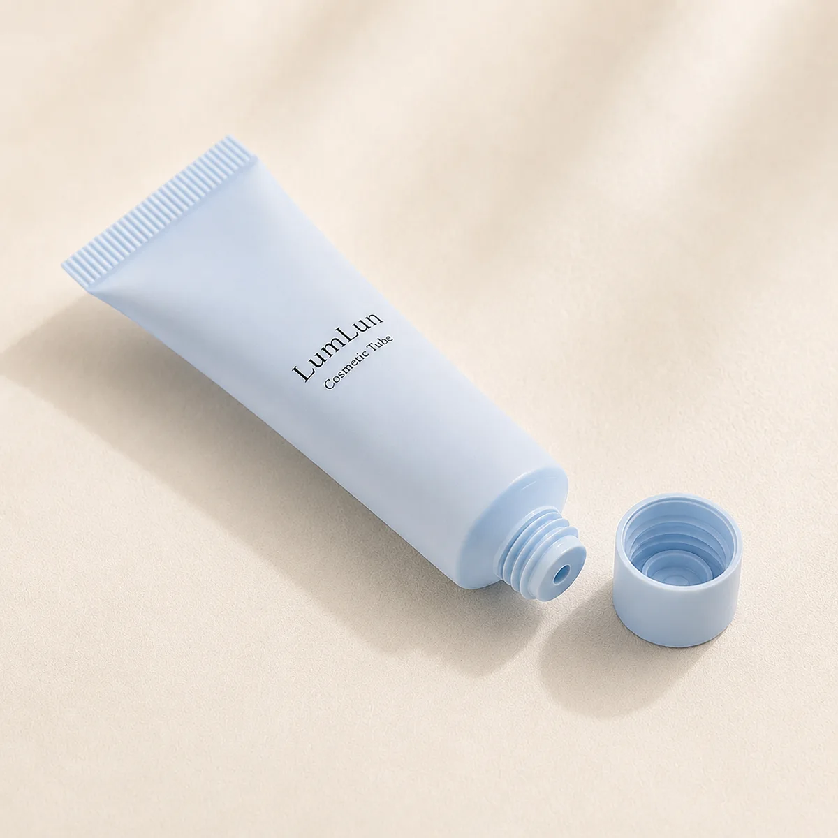 A single light blue cosmetic tube with visible open cap design displayed on a minimal soft studio background
