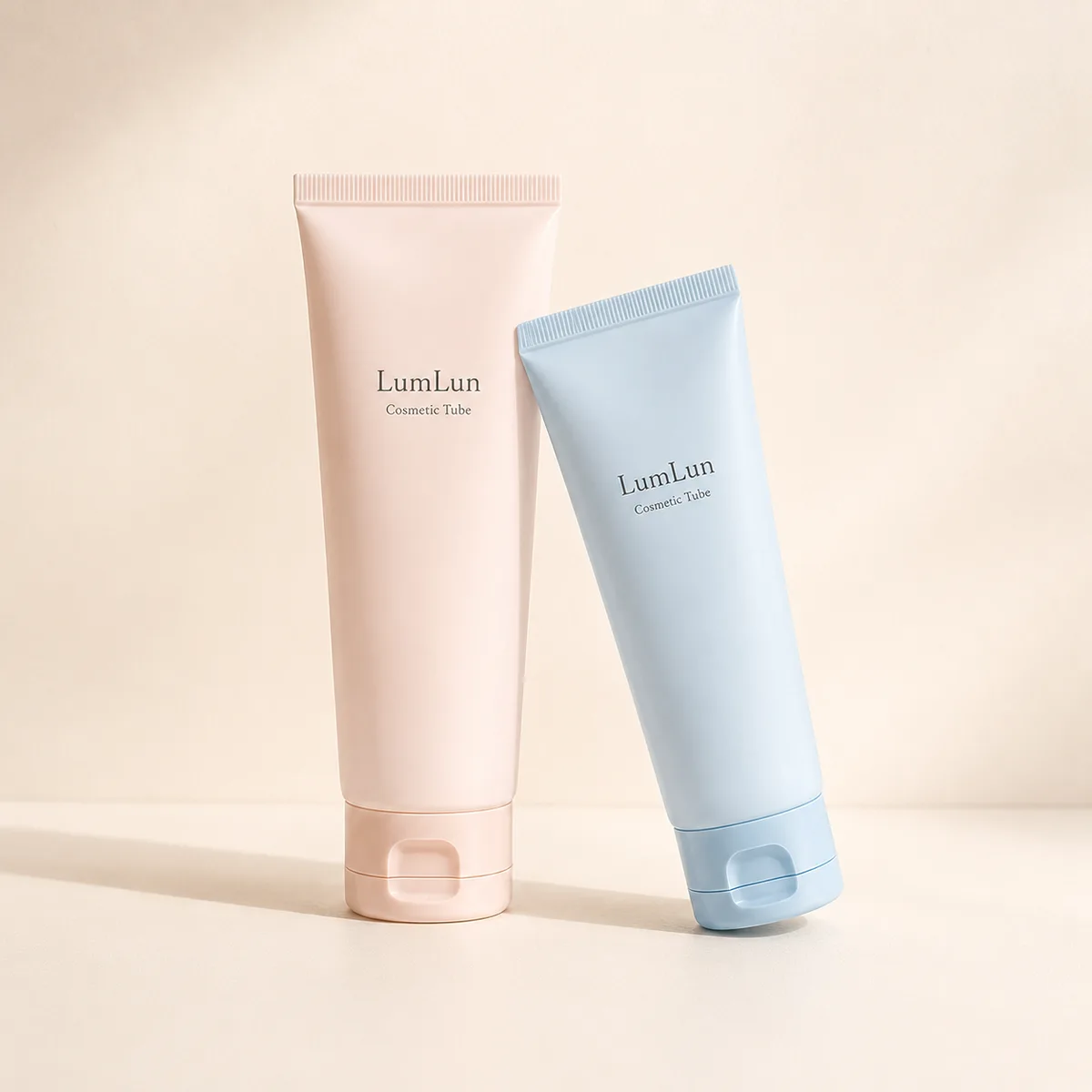 Two pastel cosmetic tubes with flip caps shown in upright and lying positions on soft neutral background