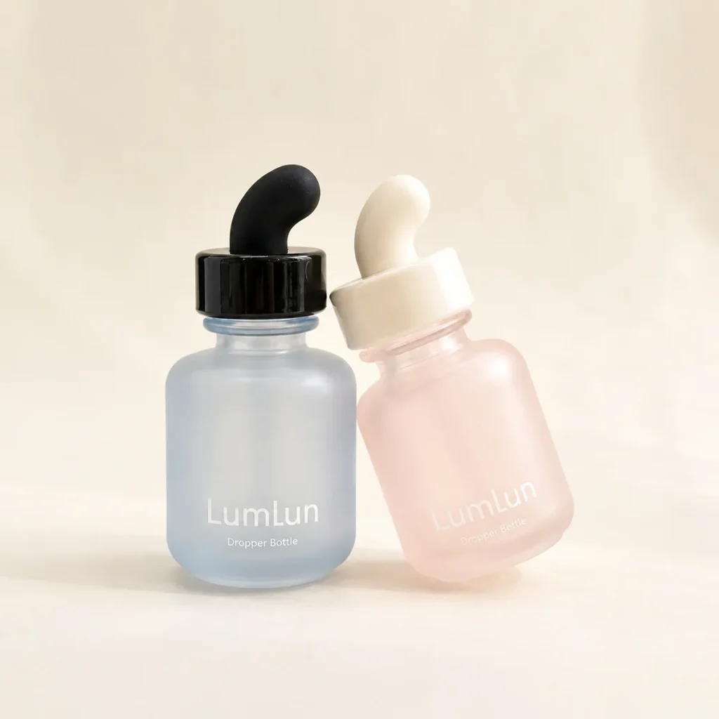 Two Lumlun curved teat glass dropper bottles in blue and pink with contrasting black and white rubber teats.