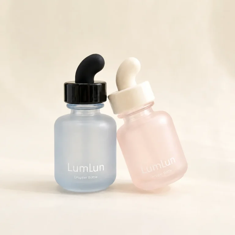 Two Lumlun curved teat glass dropper bottles in blue and pink with contrasting black and white rubber teats.