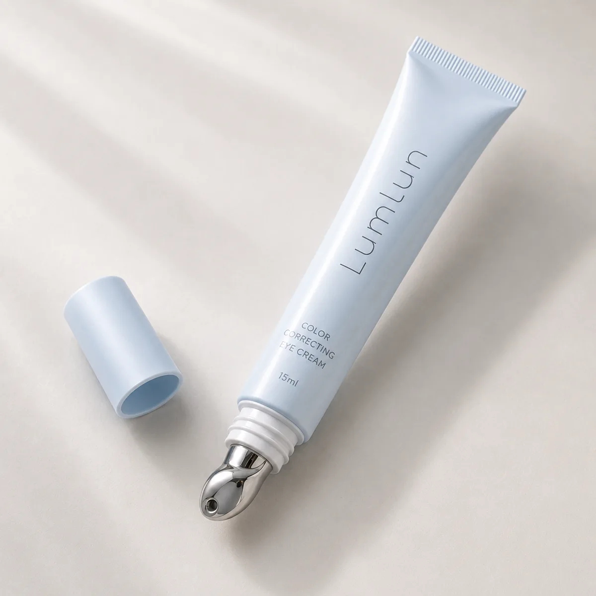 A single Lumlun eye cream tube in light blue with metal applicator tip and cap placed beside it on a clean background.