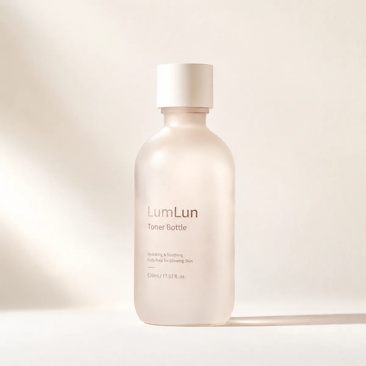 Single frosted beige toner bottle with clean cap displayed in minimal soft studio lighting