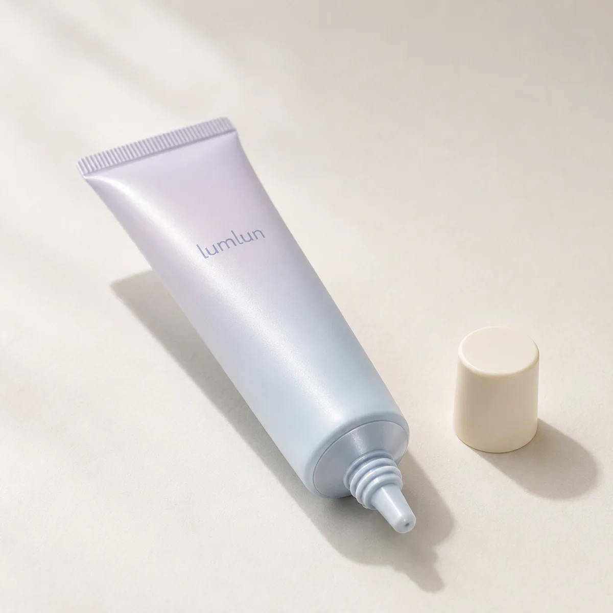 A single lavender Lumlun PE eye cream nozzle tube lying open beside a cream screw cap.
