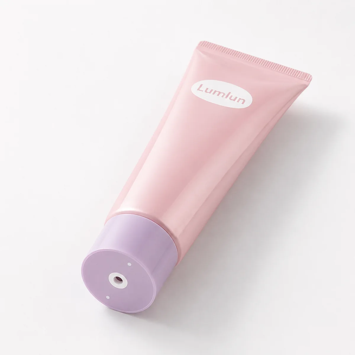 A single LumLun pink twist top cosmetic tube with purple rotary base cap displayed on a clean white studio background.