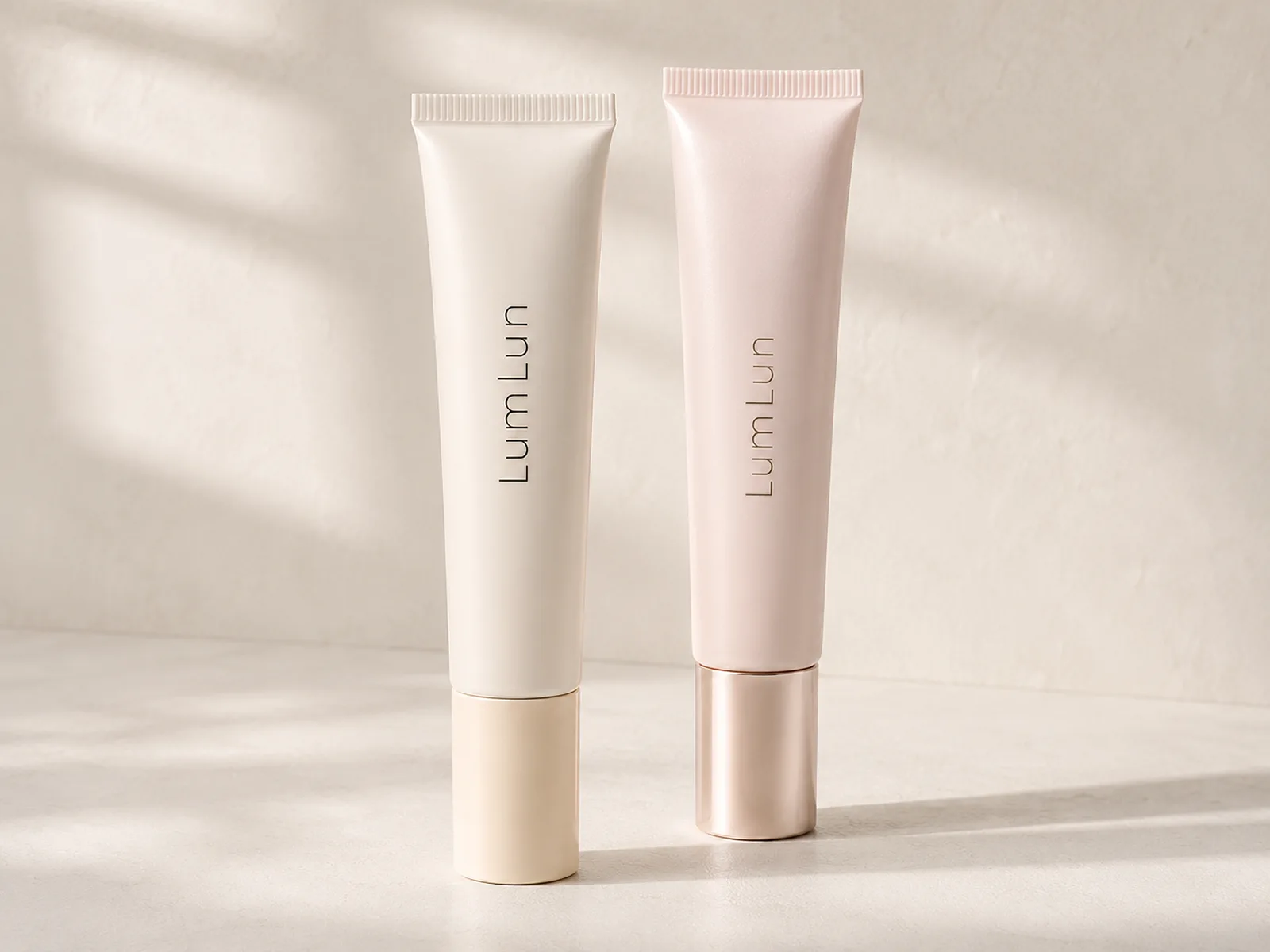 Two LumLun cosmetic soft tubes with different body colors and cap finishes for an initial two-SKU packaging direction