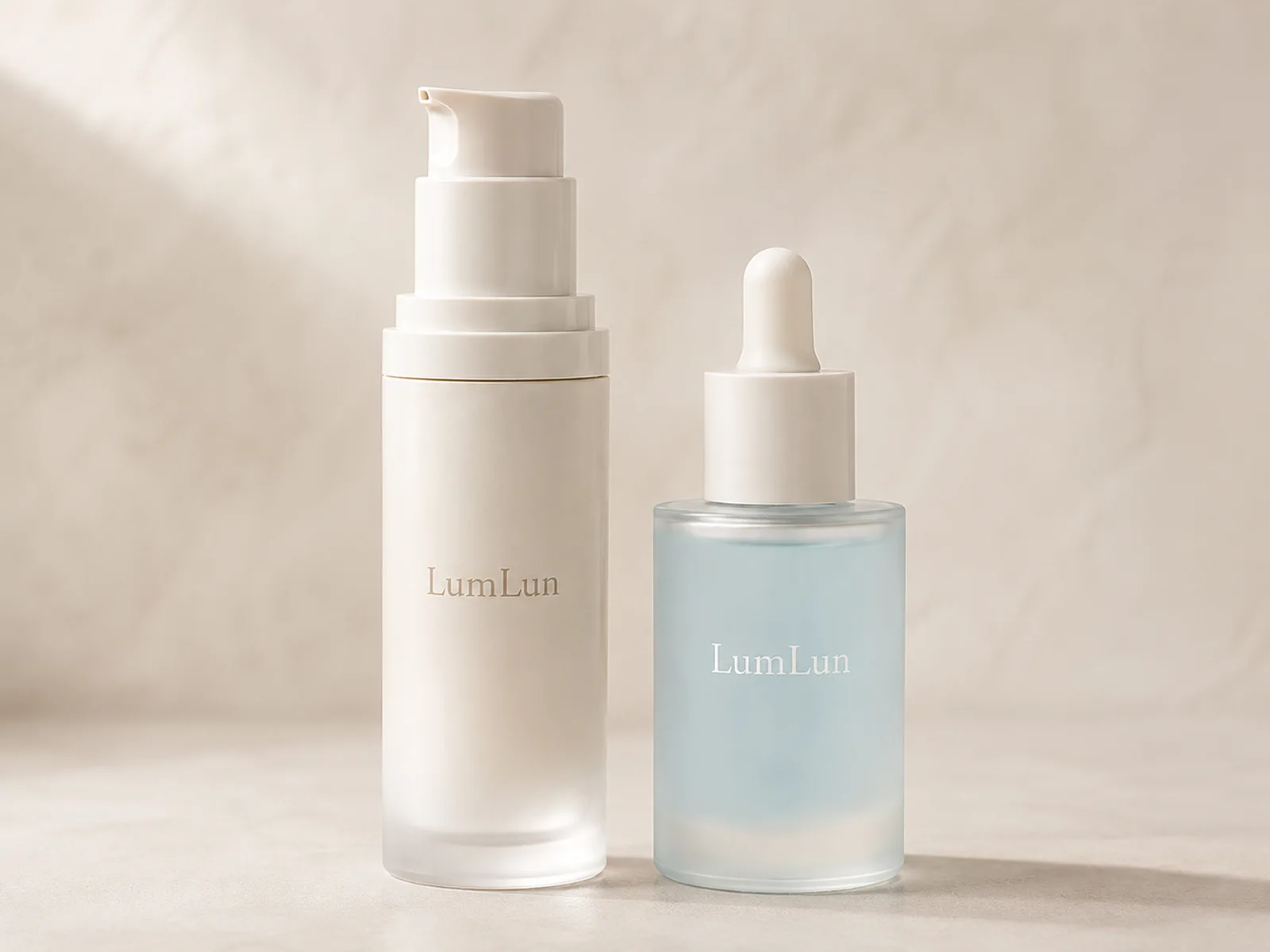 One frosted ivory LumLun airless pump bottle beside one frosted blue LumLun serum dropper bottle