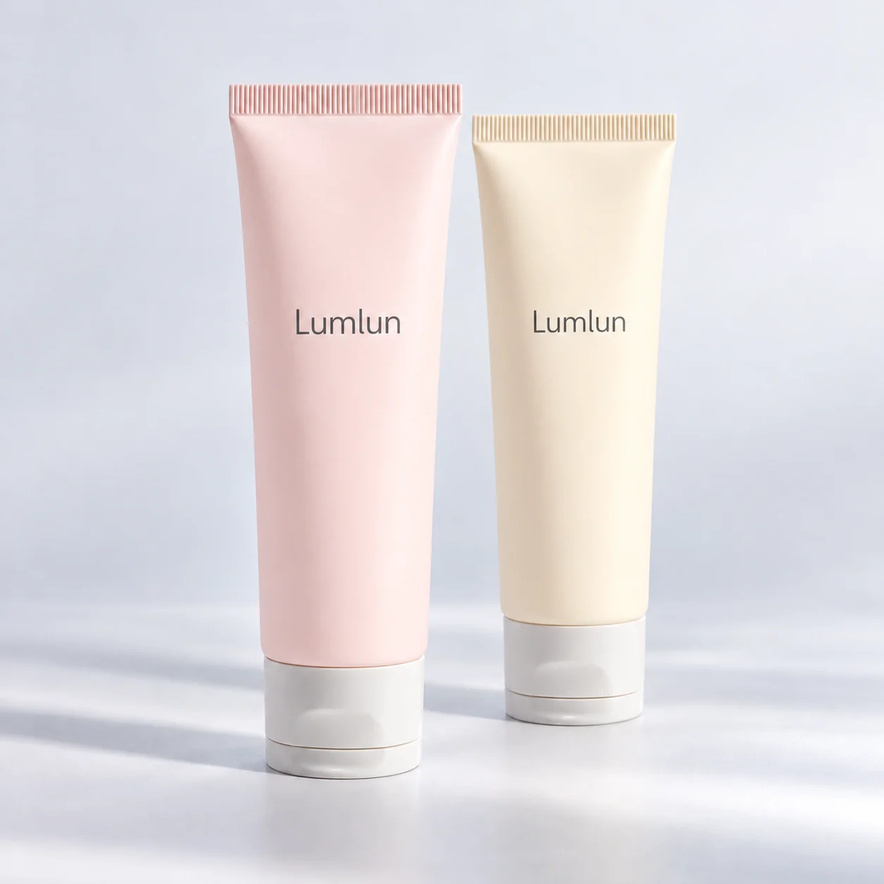 Two pink and cream-yellow cleanser tubes with light translucent caps