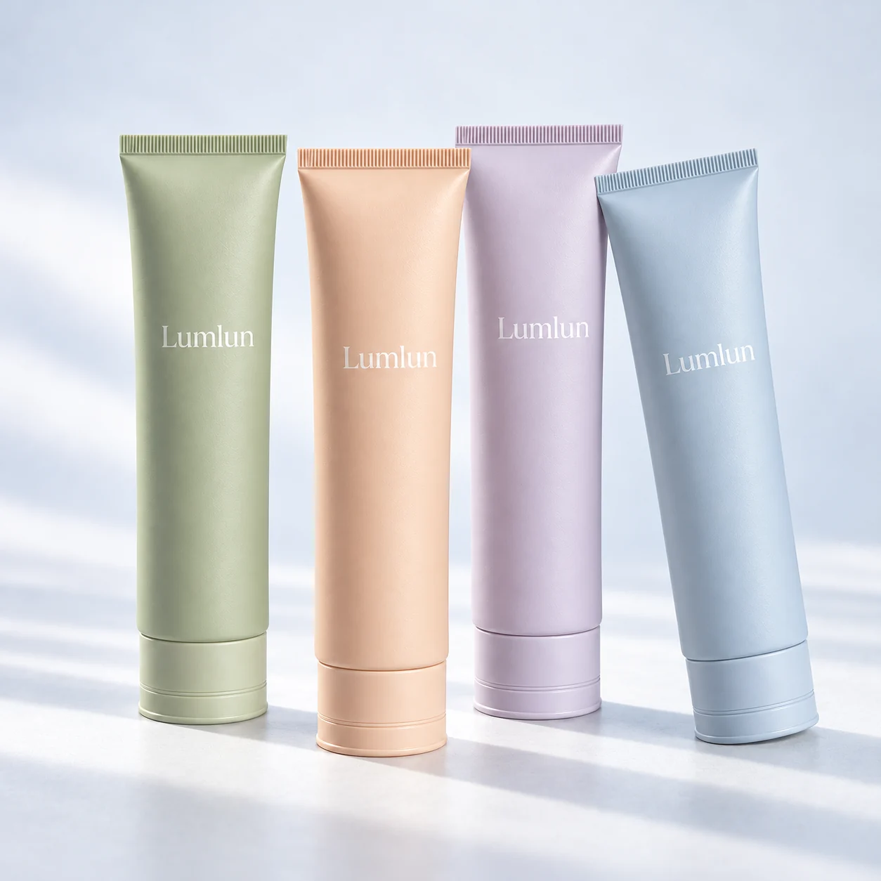 Four facial cleanser tubes in sage, peach, lavender and blue with color-matched caps