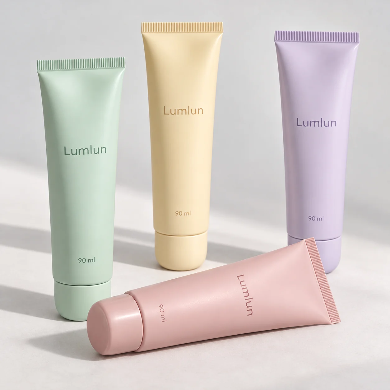 Four pastel facial cleanser tubes with darker coordinated flip-top caps, one shown horizontally