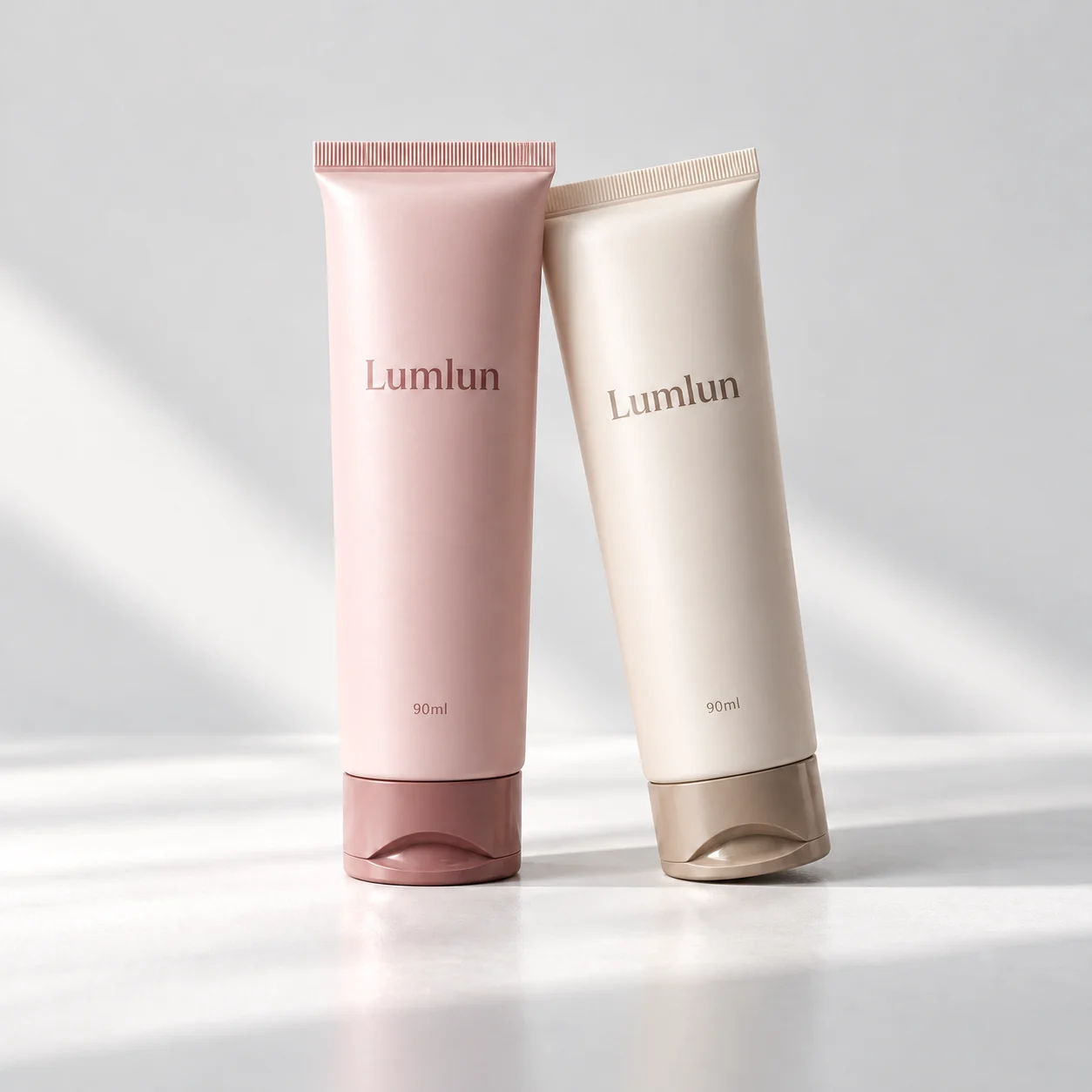 Two 40mm cleanser tubes in peach and cream with tinted caps