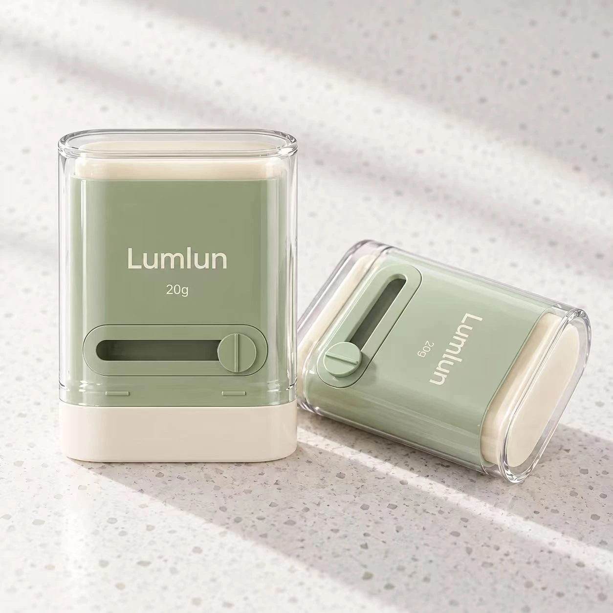 Dos envases stick LumLun de PP de 20 g en verde salvia, uno de pie y otro tumbado