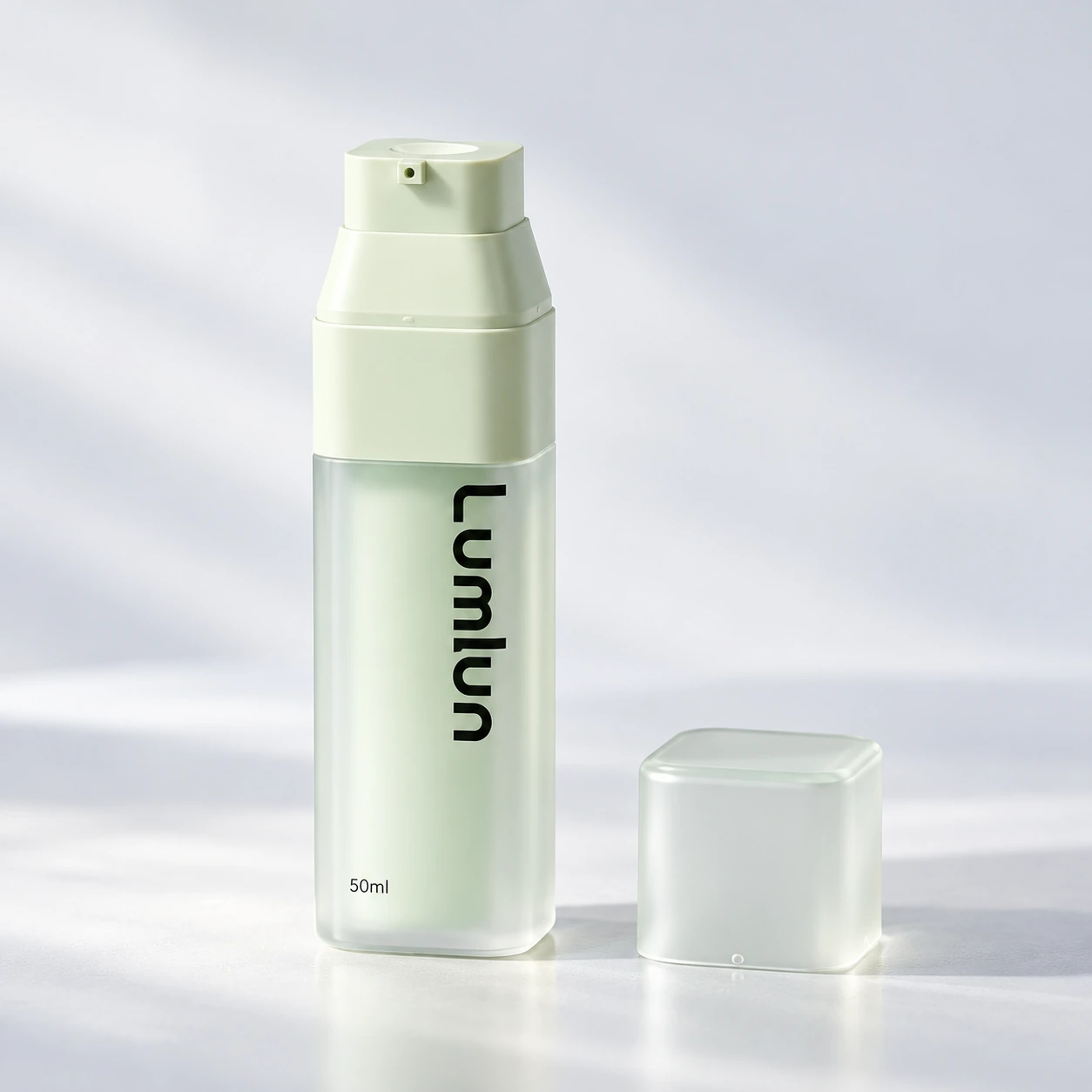 Single LumLun 50ml PP + PS square airless bottle in green with the pump exposed and translucent cap beside it