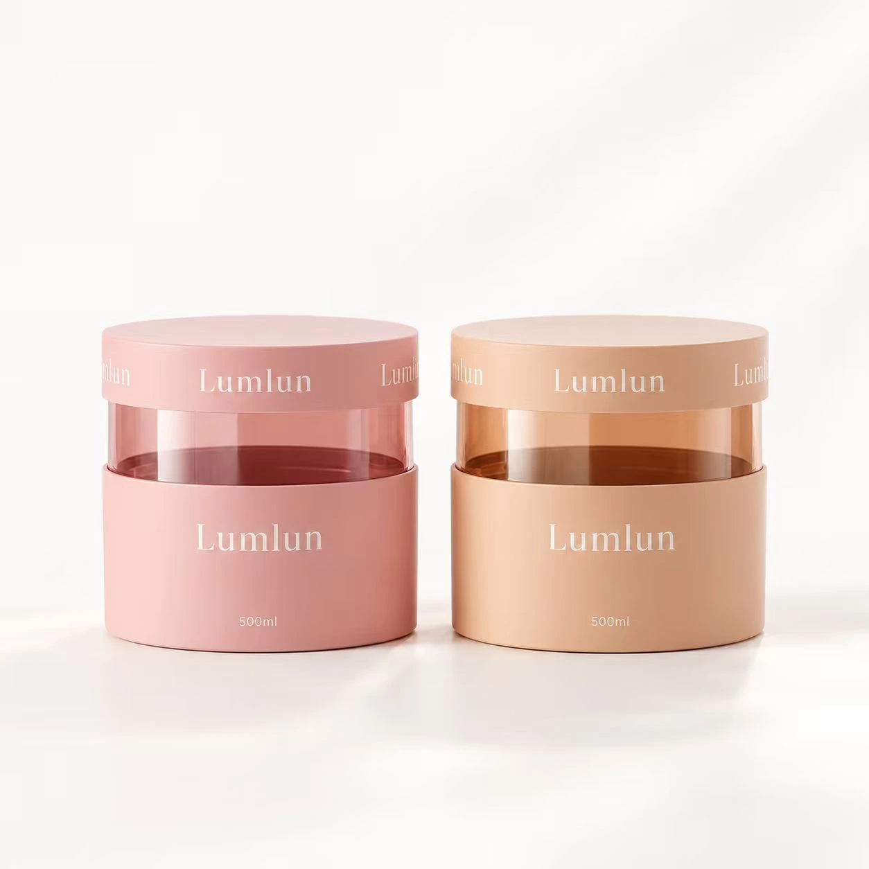 Dos tarros de crema con ventana transparente en rosa suave y melocotón, ambos de 500 ml.