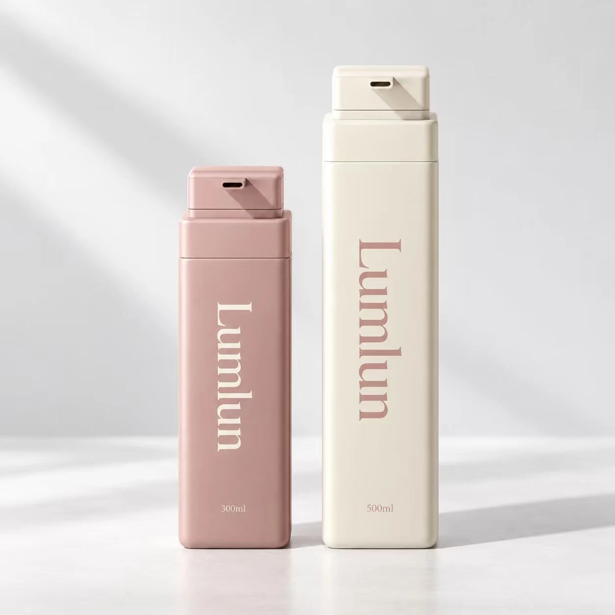 Zwei große rechteckige PET-Waschflaschen in zartem Rosa und Creme mit 300 ml und 500 ml.